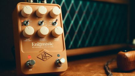 A photo of the Universal Audio Enigmatic ’82 Overdrive Special Amp pedal in shadow alongside a vintage Dumble amplifier and an electric guitar