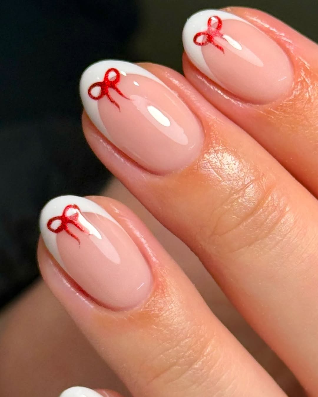 a french manicure with tiny red bow designs