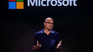 Satya Nadella giving a speech with the Microsoft logo in the background