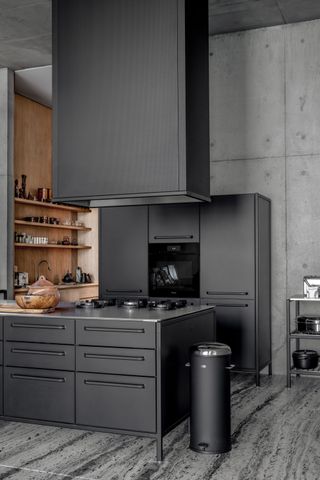 A black themed kitchen with concrete walls