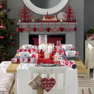 Grey dining with table and chairs and fireplace, with red Christmas decorations