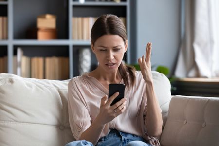 Woman holding a mobile phone looking annoyed