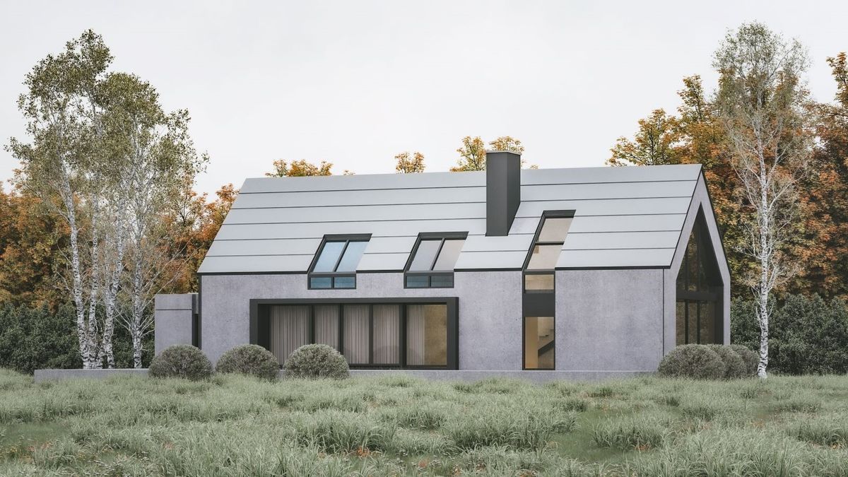 A house with a metallic grey pitched roof and rendered grey walls with large amounts of glazing. It is sitting on a countryside plot