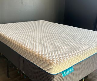 The Simba Hybrid Pro Mattress against a dark green wall.