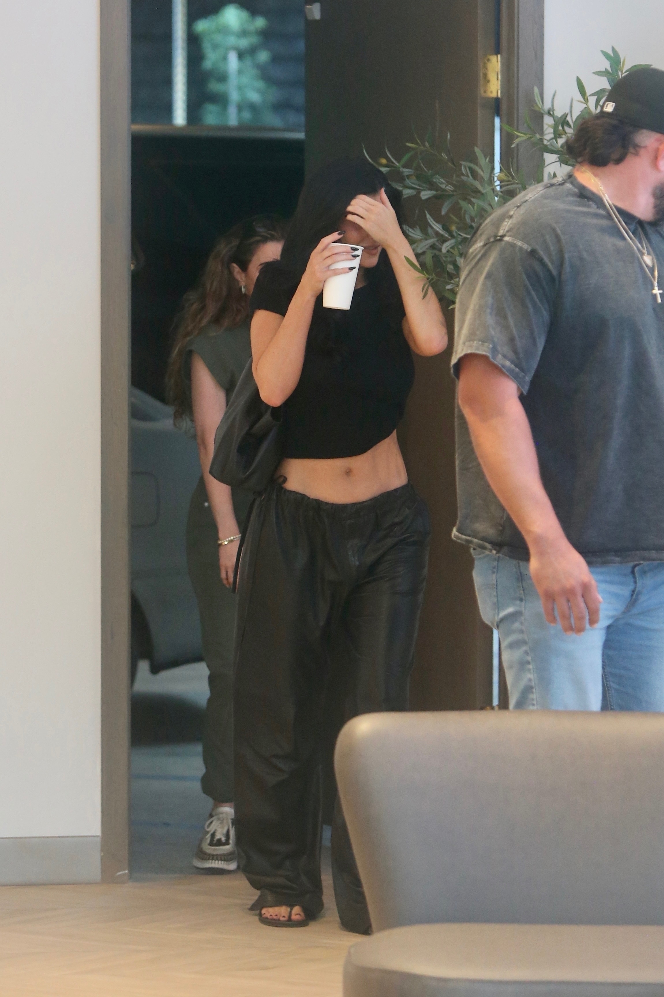 Kylie Jenner and Hailey Bieber wear heeled flip flops and baggy black pants