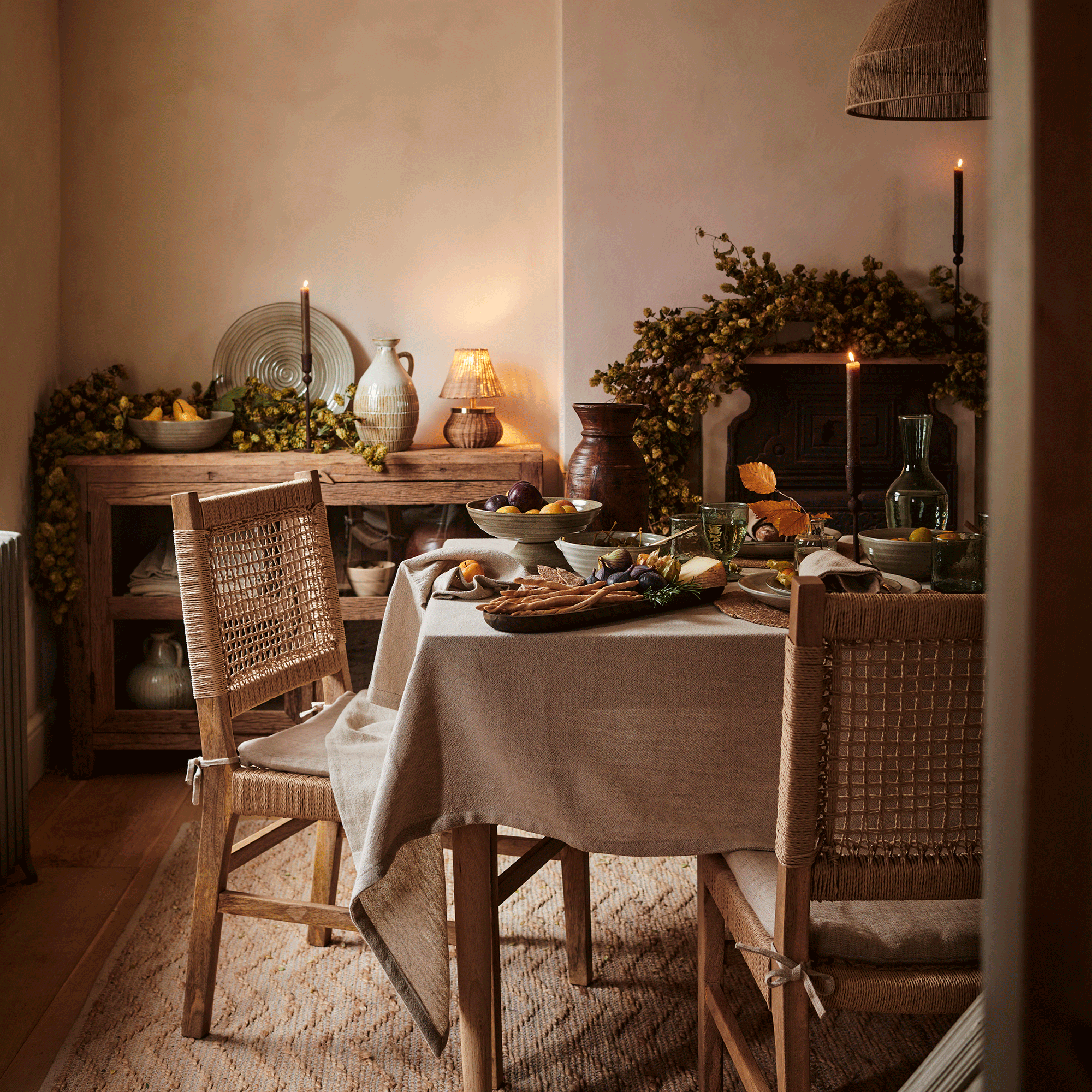 Autumnal dining table with woven chairs and a wooden dresser