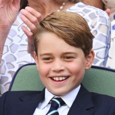 Prince George wearing a suit and tie and smiling at Wimbledon