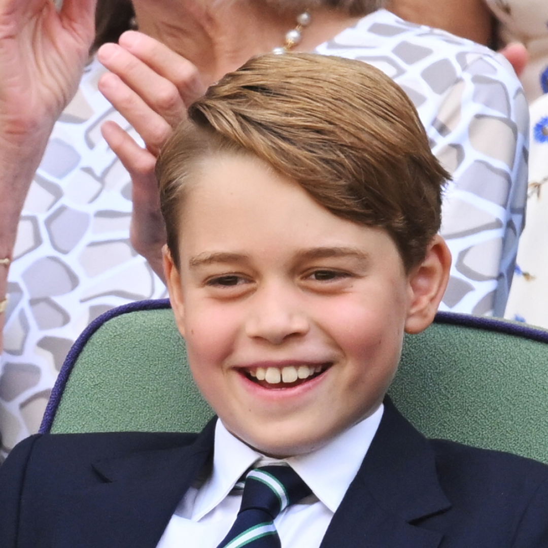 Prince George wearing a suit and tie and smiling at Wimbledon