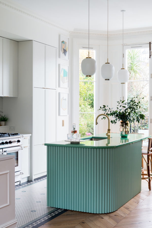 A kitchen with a blue island, and white island lights above
