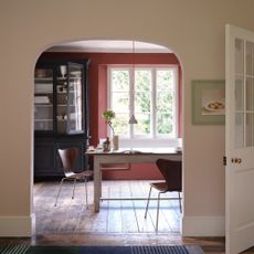 An arched entrance into a rustic dining room with the surrounding wall painted in Scallop