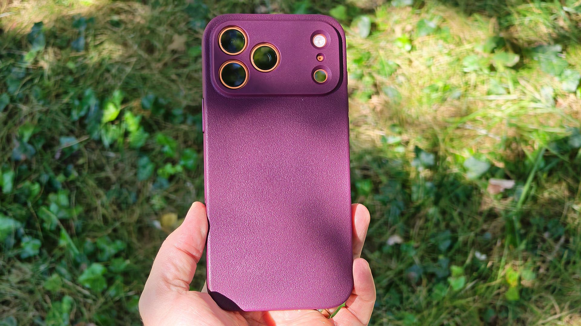 A burgundy Dbrand MNML case on an orange Apple iPhone 17 Pro Max