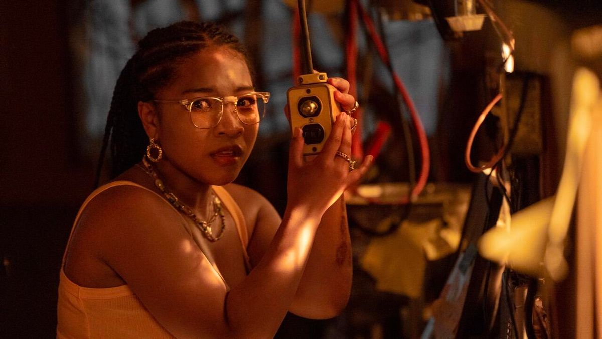 A woman looks nervously towards the camera while holding a large switch