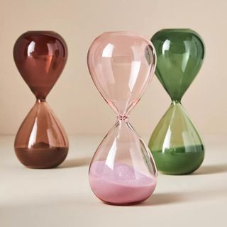 Three ombre colored hourglasses on a neutral backdrop