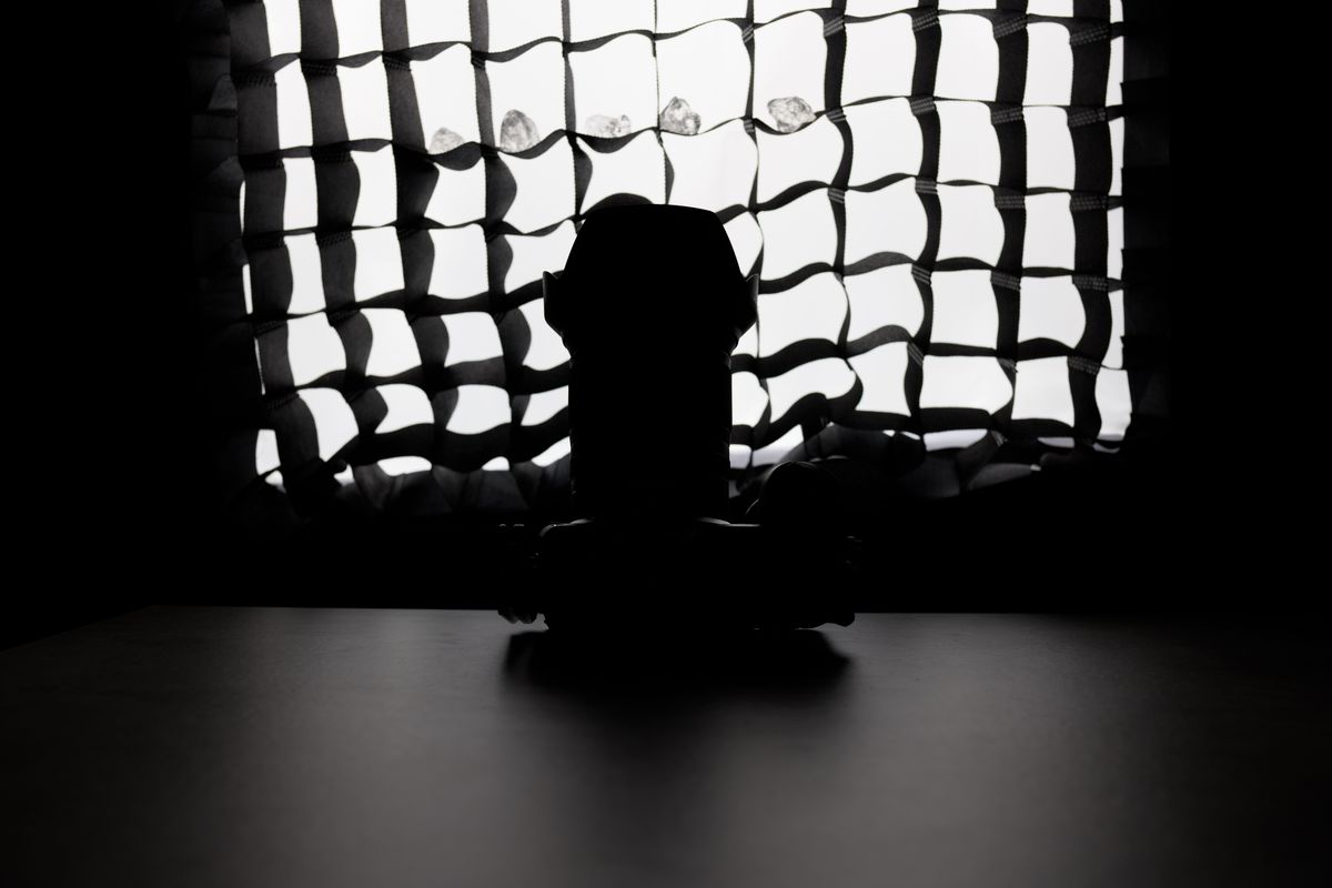A photo of a camera in front of a softbox, obscured by shadow