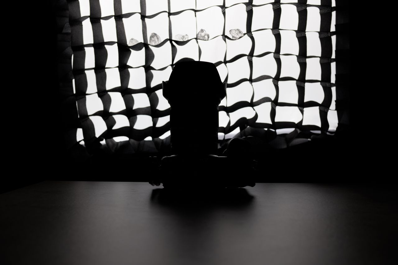 A photo of a camera in front of a softbox, obscured by shadow