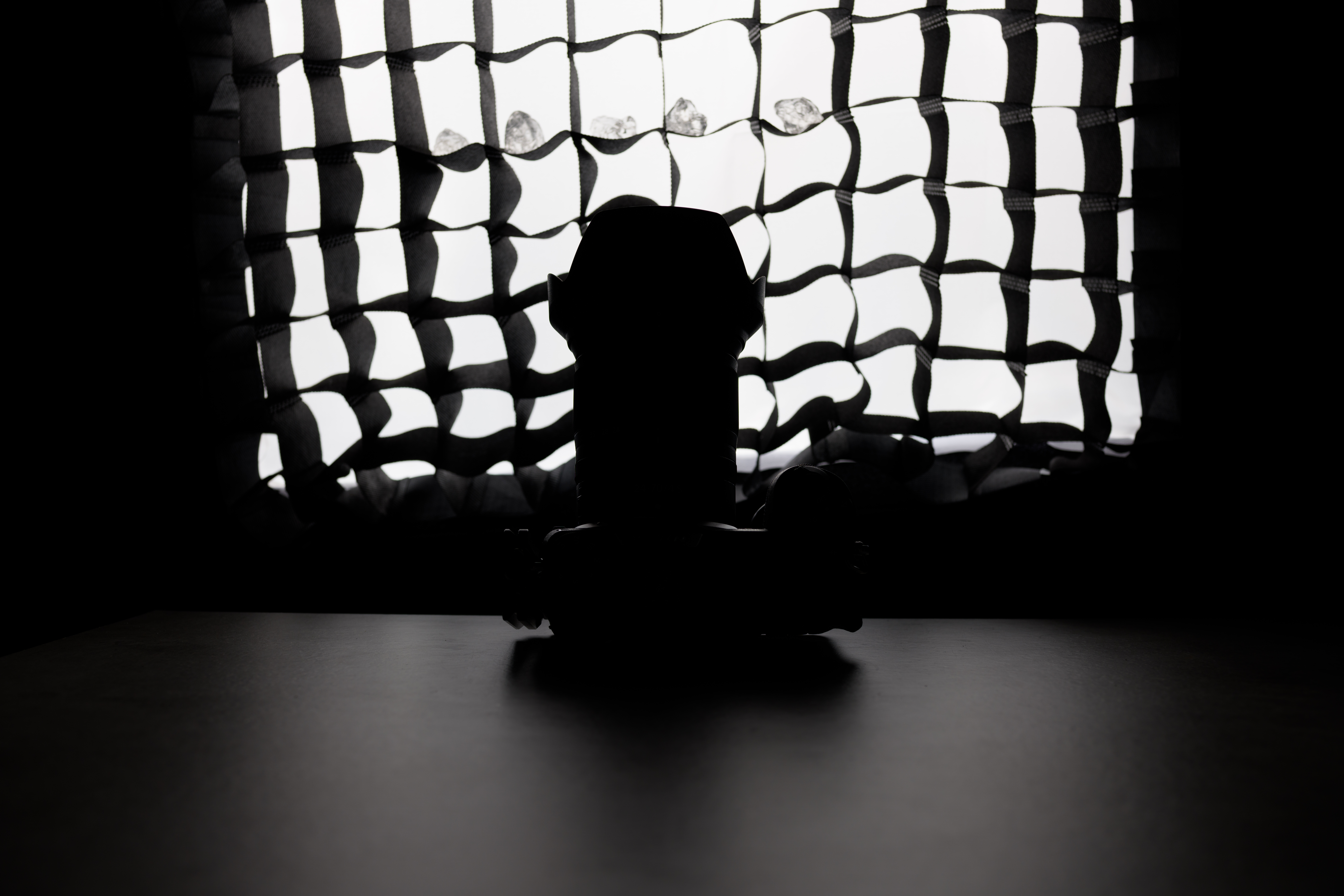 A photo of a camera in front of a softbox, obscured by shadow