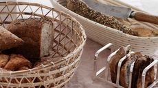 Wicker basket with loaves of bread next to metal rack of bread slicers
