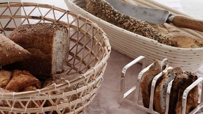 Wicker basket with loaves of bread next to metal rack of bread slicers
