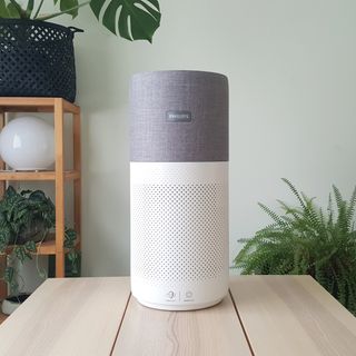 The Philips 3000i Series AC3033/30 Connected Air Purifier on a wooden table in a green room with lots of indoor plants