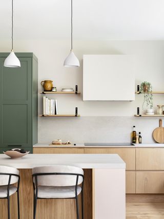 scandi kitchen with white cabinetry wooden island and base cabinets and green larder
