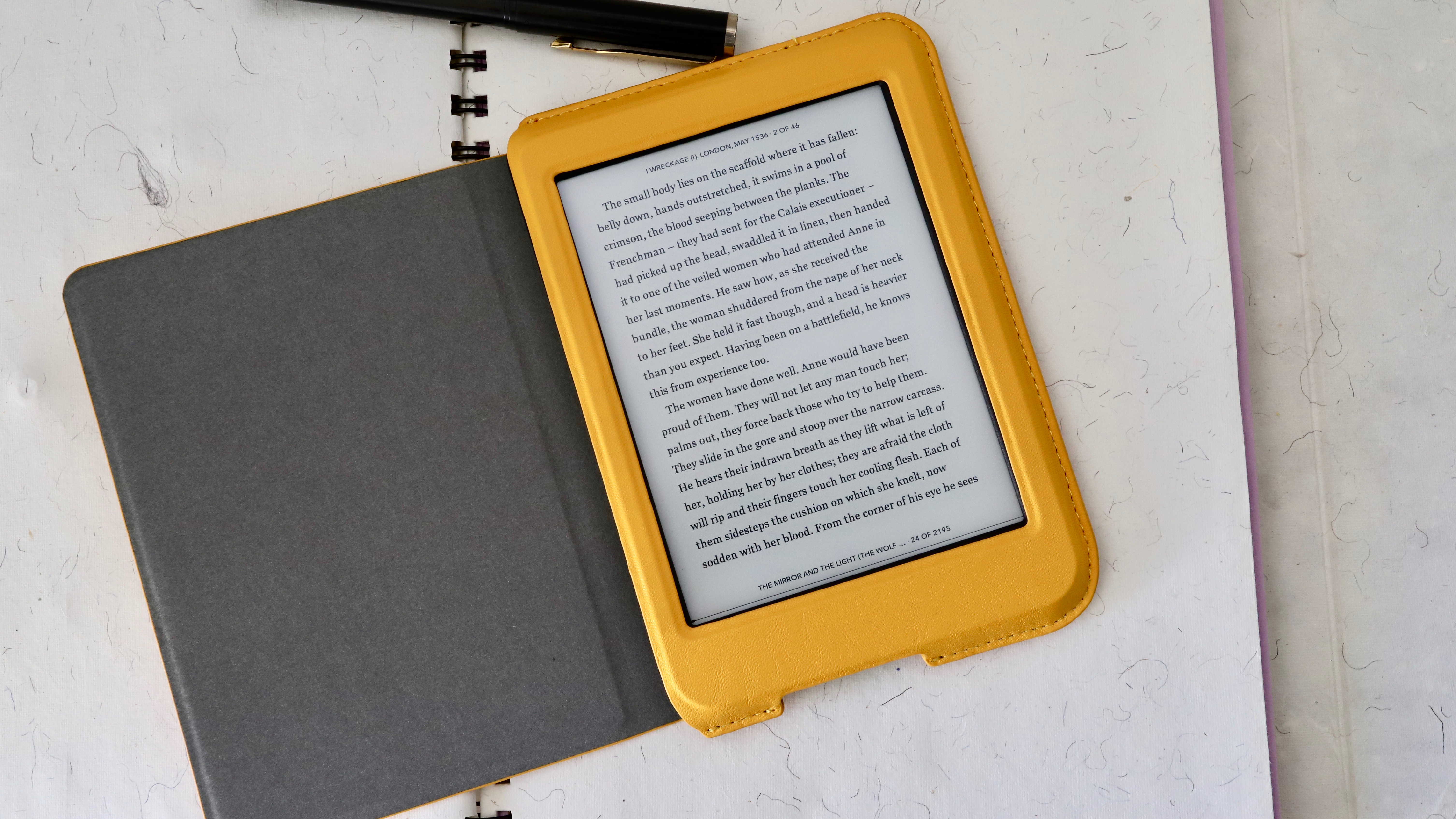 En gul Kobo Nia med tændt skærm ligger på en tom notesbog