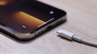 iPhone 13 on a table with a Lightning cable by its charging port