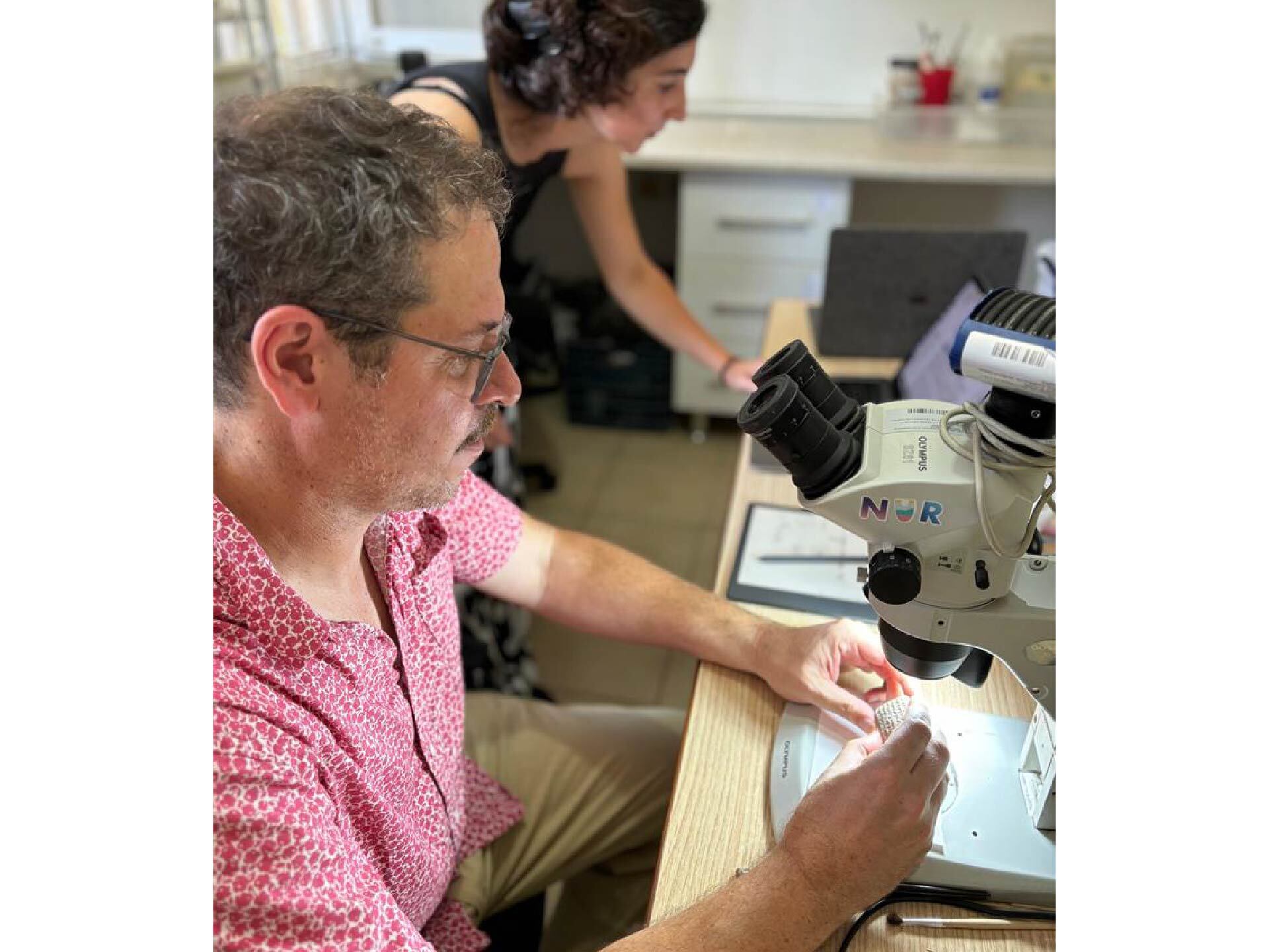 two scientists observing the cuneiform tablet under the microscope to decipher the inscription