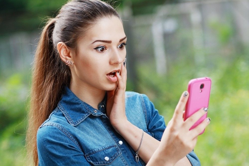 A woman looking surprised at her smartphone.