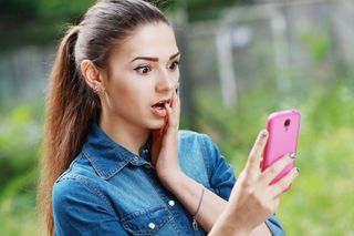 A woman looking surprised at her smartphone.