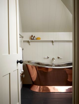 Neutral attic bathroom with shiplap paneling and a freestanding copper bath