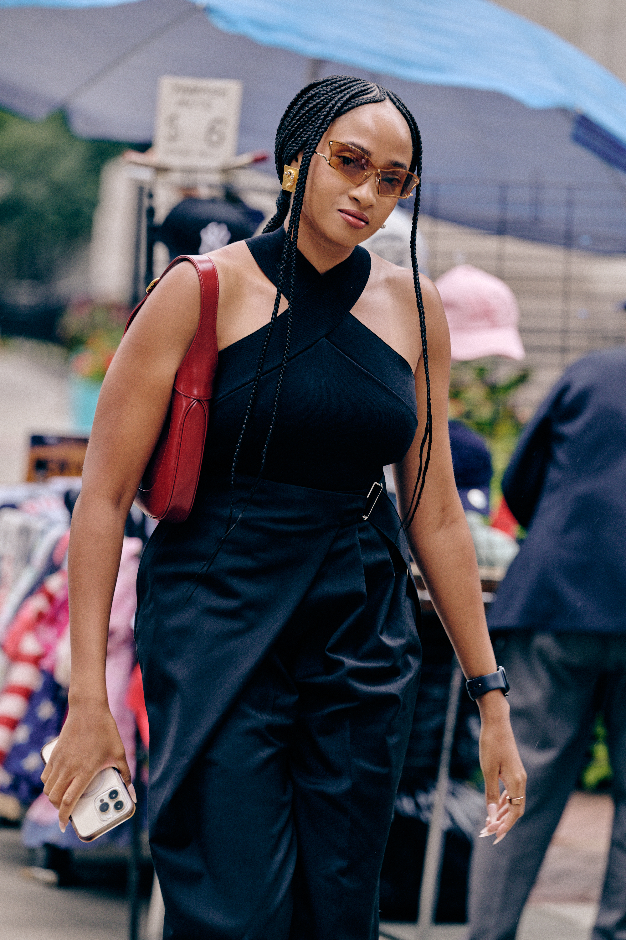 a woman wearing orange y2k sunglasses, a black halter top, and black pants