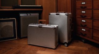 Two hammered metal suitcases in a wood-lined room