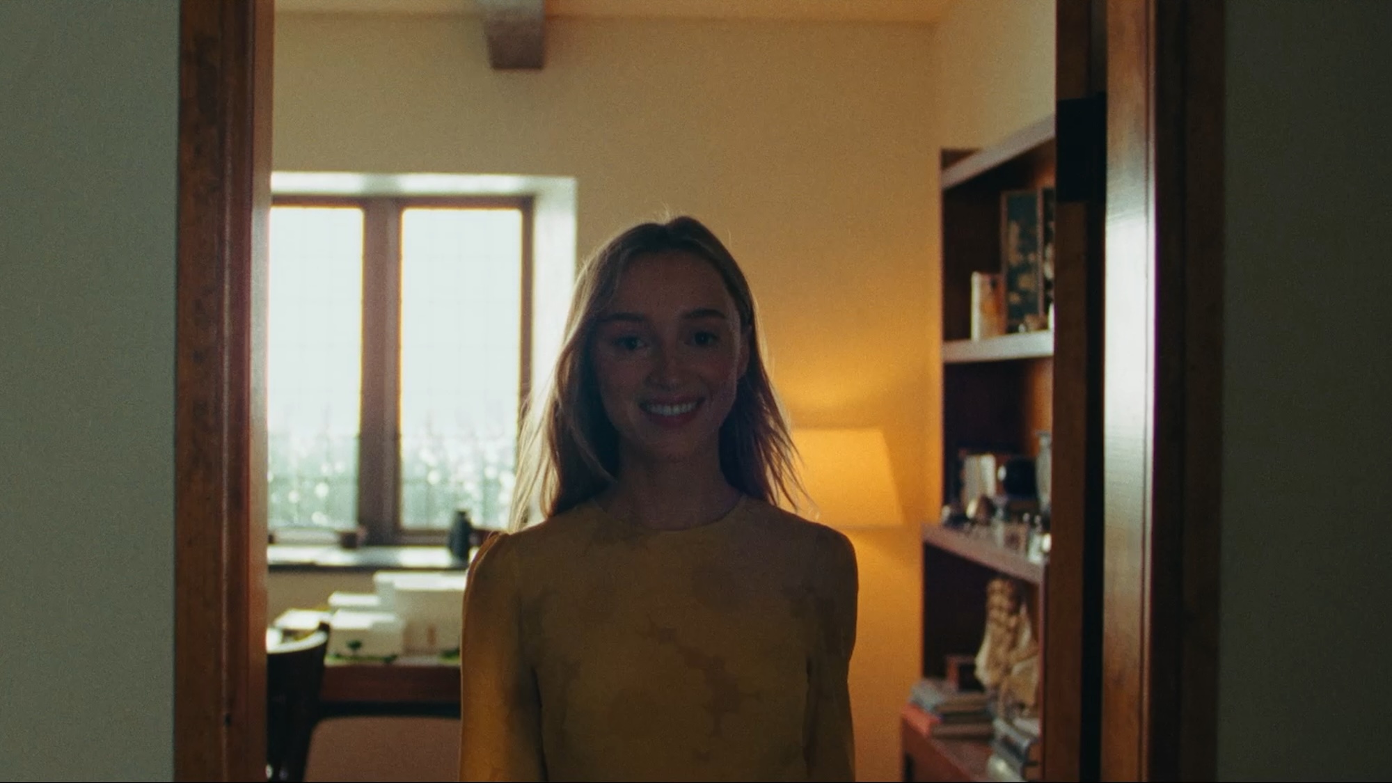 Phoebe Dynevor smiling in a doorway in Remain