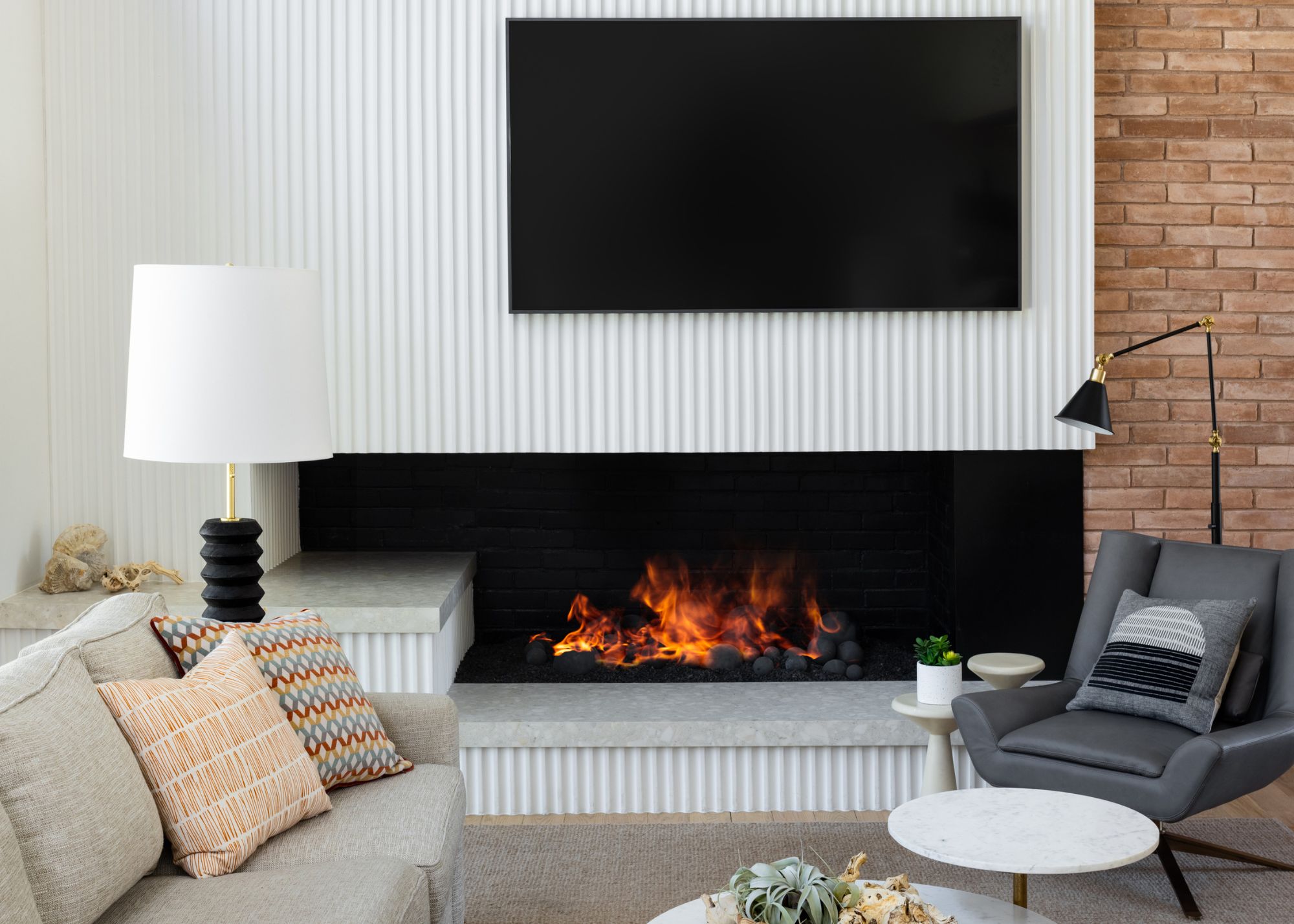 A living room with a white fluted TV wall, a fireplace and a couch
