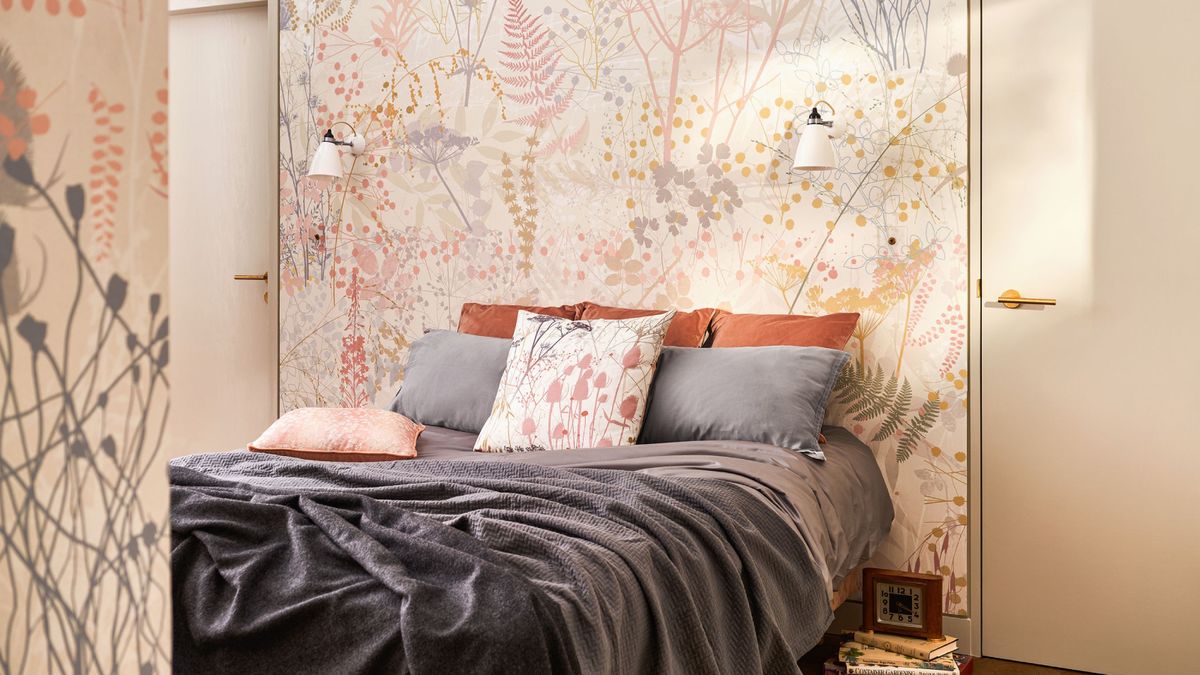 bedroom with floral wallpaper in coral and cream, bed with grey blanket and cushions