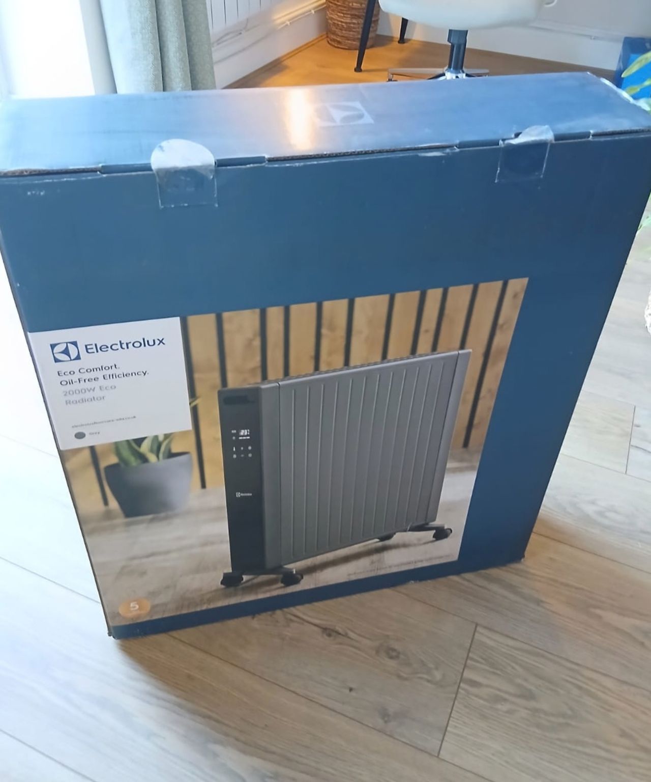 Blue Electrolux 2000W Eco Radiator box with a product photo, standing on a wooden floor.