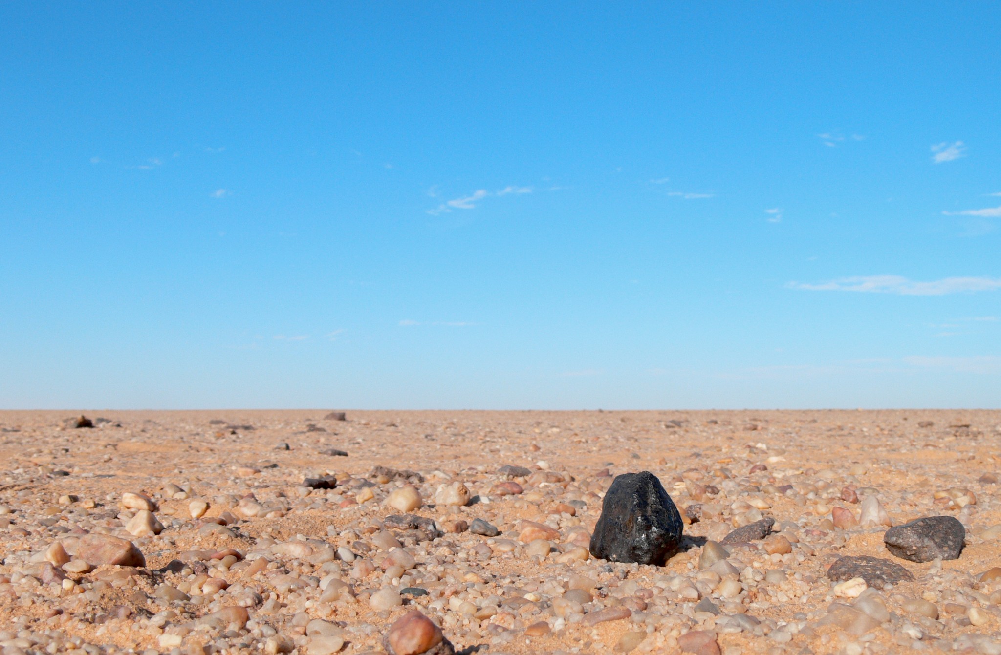 The black fragment of Almahata Sitta meteorite number 15 shows up black against the lighter coloured rocks of the Nubian desert in northern Sudan.