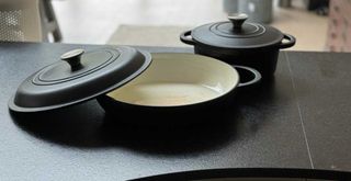 Matt black cast iron cookware on a black kitchen countertop