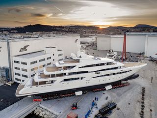 CRN shipyard featuring one large yacht on display in a square and a sunset landscape of Anoca, Italy