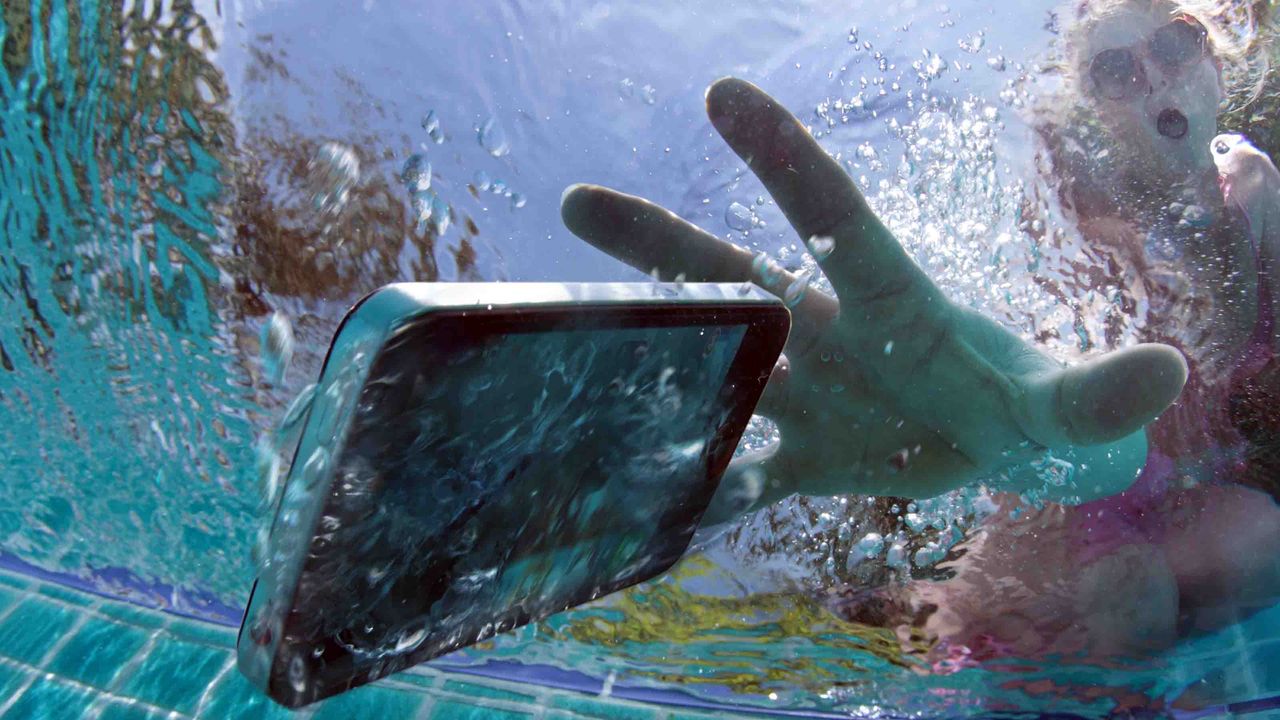 A person looks surprised as they realize they&amp;#039;ve dropped their iPhone in the pool