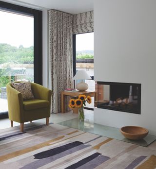 white wall with inset log burning stove near chair and glazing