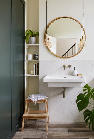 Ideas for small bathrooms: Broch. Bathroom with marble-effect tiles halfway up the wall, a round mirror framed either side with bare bulb pendant lights, and a wood-effect flooring