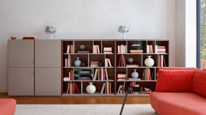 living room with large bookcase and sofa with living coral shade by ligne roset