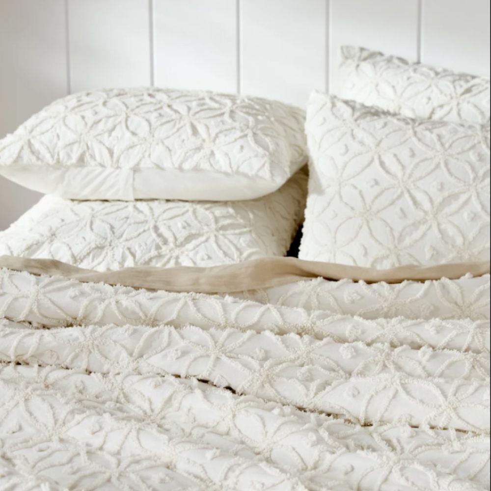 Ivory coloured tufted quilt and pillow set on a bed