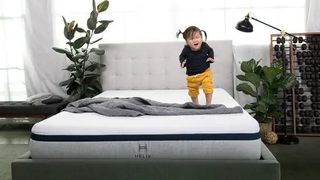 A little girl with pigtails jumps on the Helix Midnight Mattress