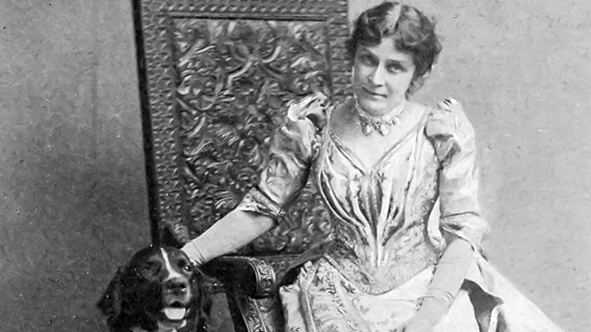 Black and white photo of Eunice Foote sitting in a chair, one hand on the head of a dog sitting next to her.