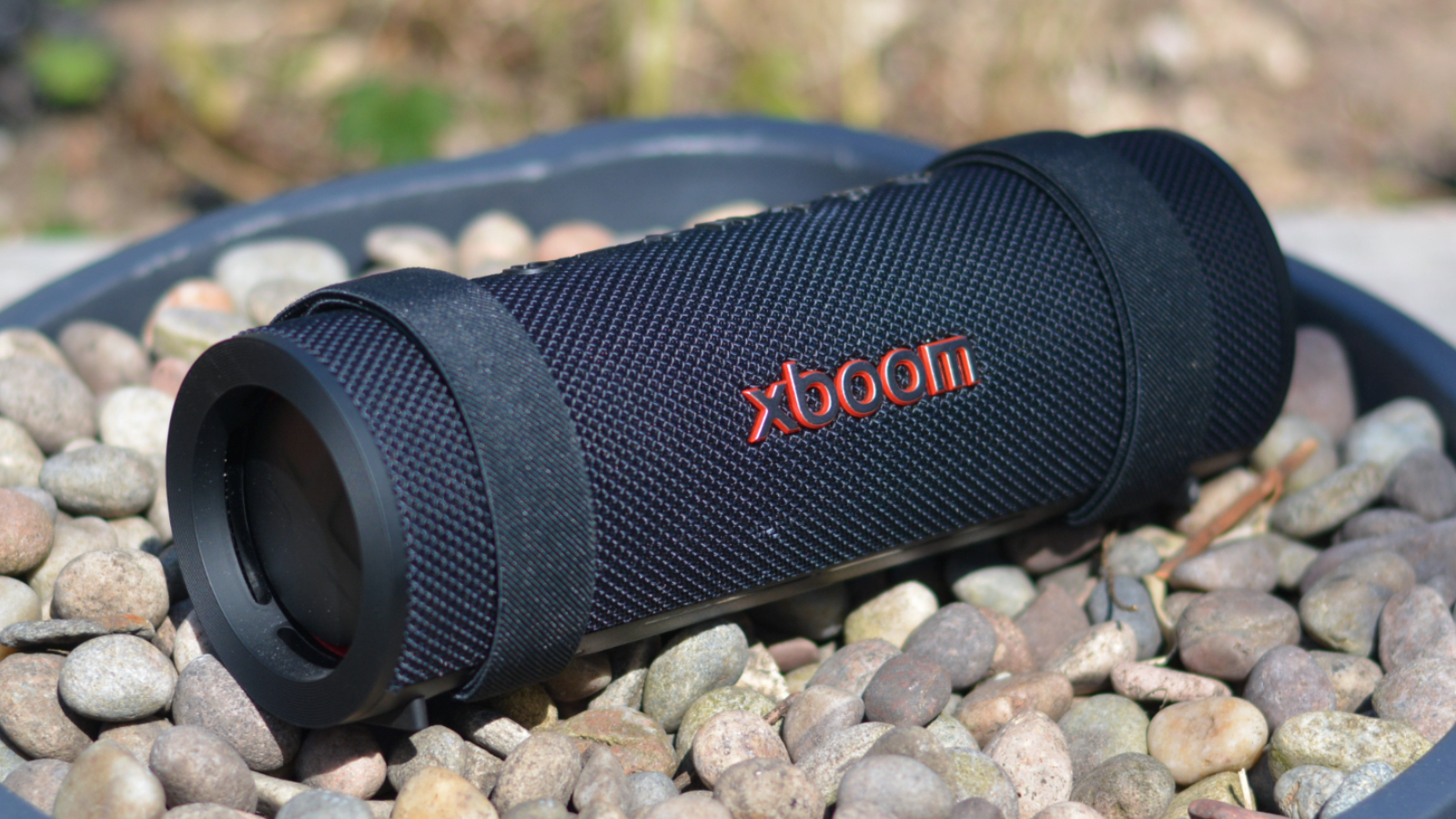 LG xboom Grab Bluetooth speaker in an outdoor setting