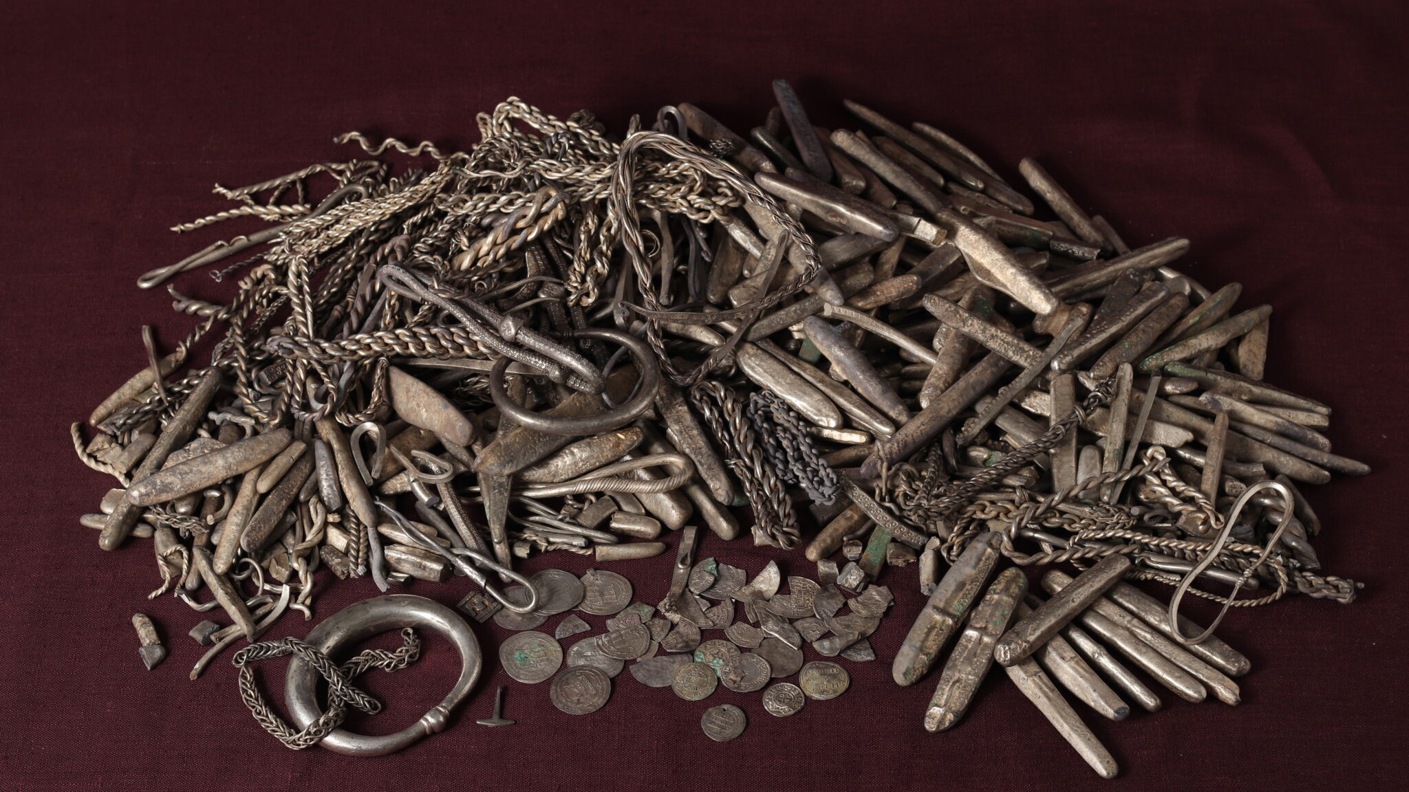 A close up of metal items from a Viking hoard against clean surface