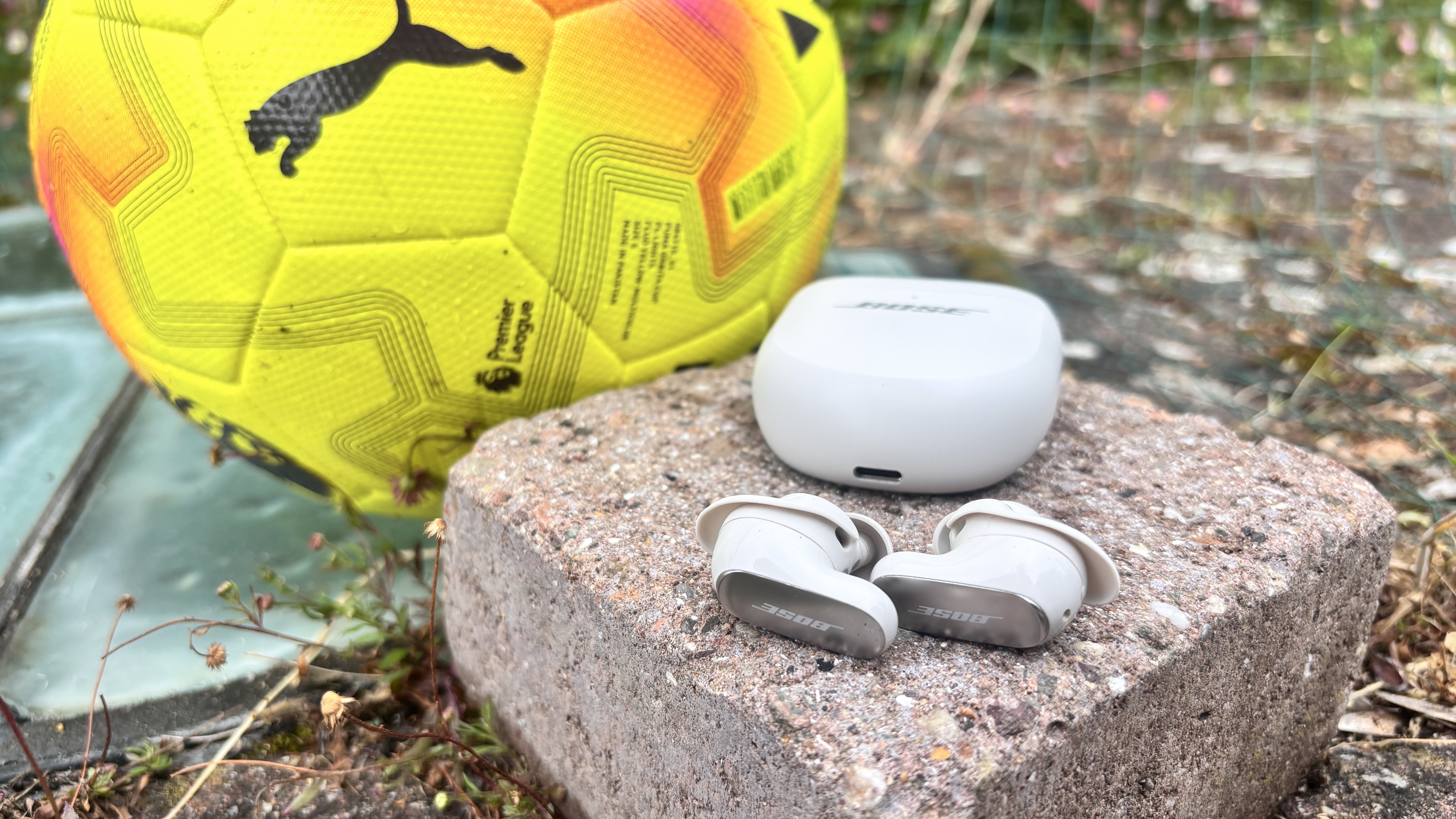 Bose QuietComfort Ultra Earbuds (2nd Gen) wireless earbuds next to a yellow football