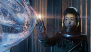Shioli Kutsuna, dressed in a space suit, touches a floating supernatural globe in a scene from Invasion season 2 on Apple TV Plus.